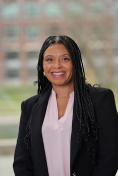 Tamika Dawson-Knox smiling, wearing professional attire, in front of a window