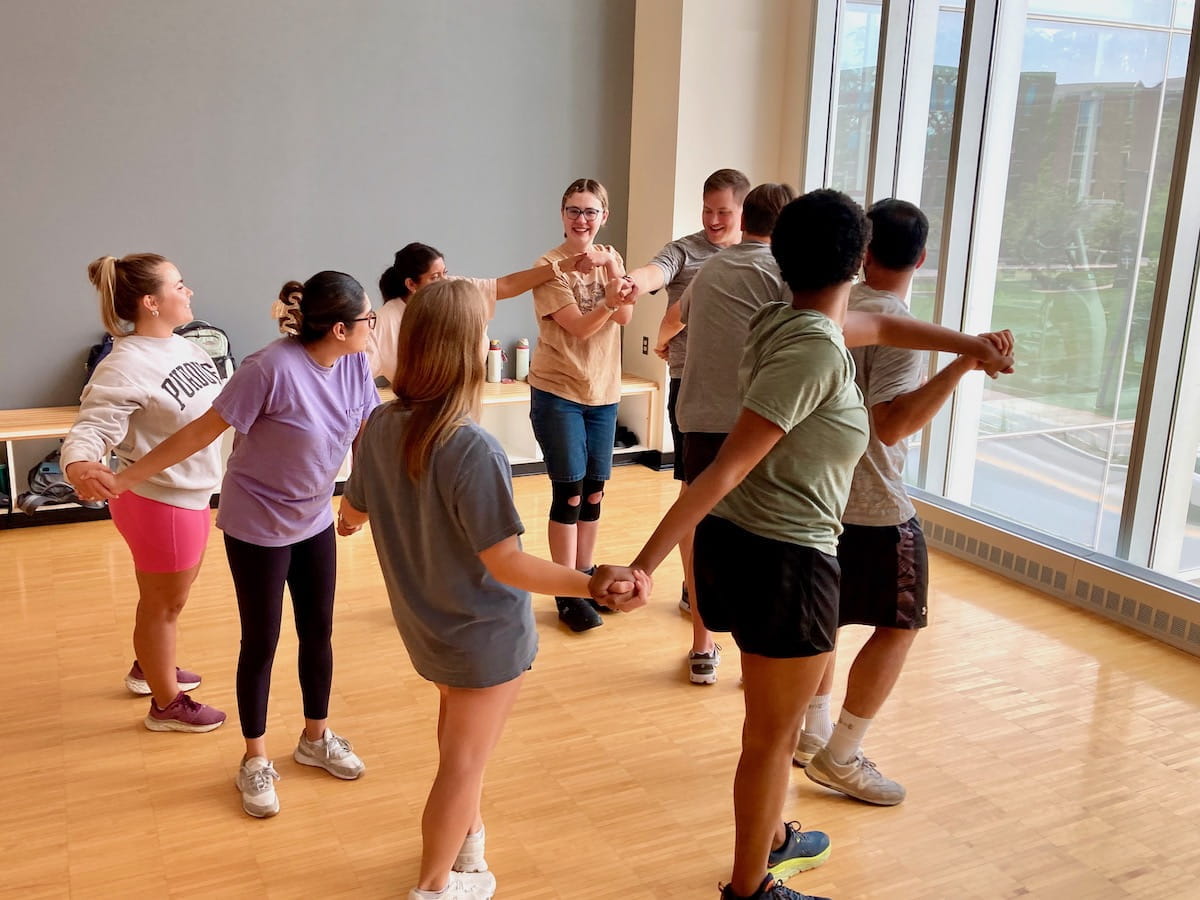 Sarah Vaught and West Lafayette classmates stand in a circle with arms locked during a team building exercise at orientation.