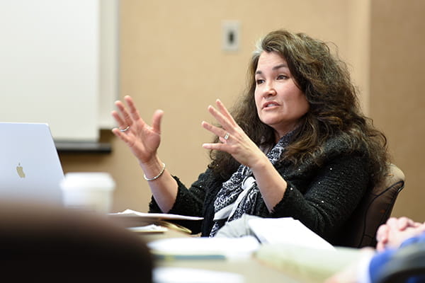 A female faculty member speaks during a research meeting