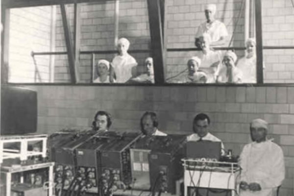Black-and-white photo of technology and medical experts collaborating on a surgery demonstration, recorded for television at the ISMA Centennial Convention in September 1949.