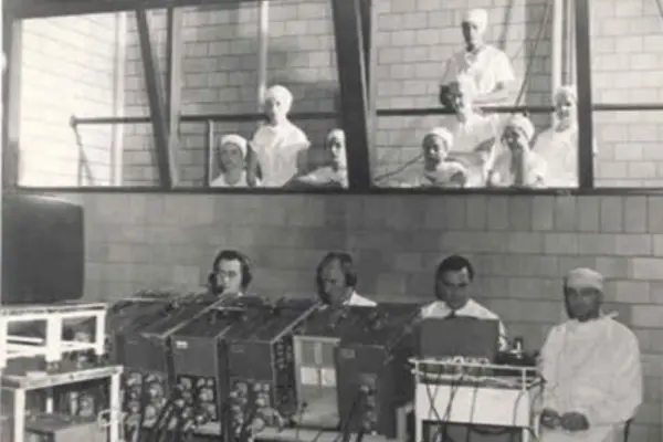 Black-and-white photo of technology and medical experts collaborating on a surgery demonstration, recorded for television at the ISMA Centennial Convention in September 1949.