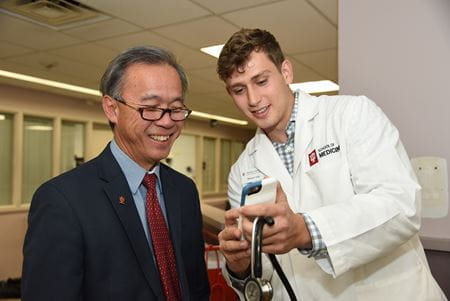 Taihung "Peter" Duong talks with a medical student at IU School of Medicine—Terre Haute. | Photo by Tim Yates, IU School of Medicine Dr. Duong laughs while looking at a handheld device with a medical student