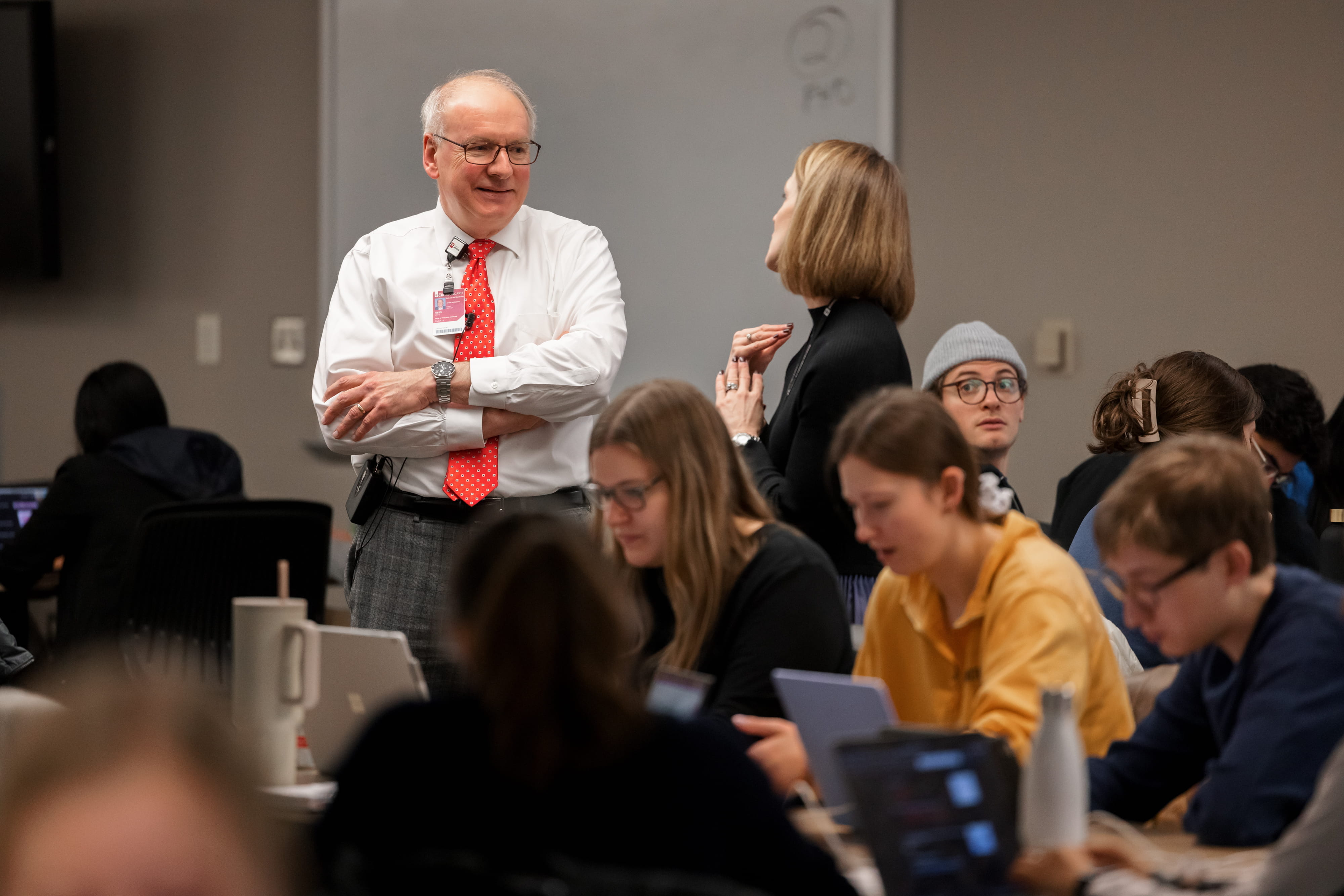 Dean Jay Hess talks with a professor in a classroom of medical school students.