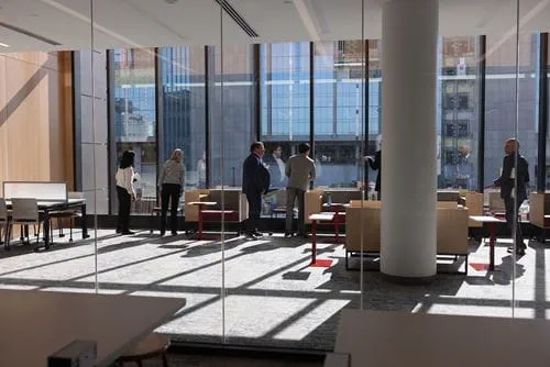 A group of people check out study spaces at the new Medical Education and Research Building with a window view of the IU Health Downtown Hospital.