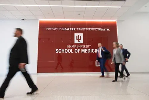 IU President Pamela Whitten and others walk past a wall with the IU School of Medicine log illuminated at the new Medical Education and Research Building.