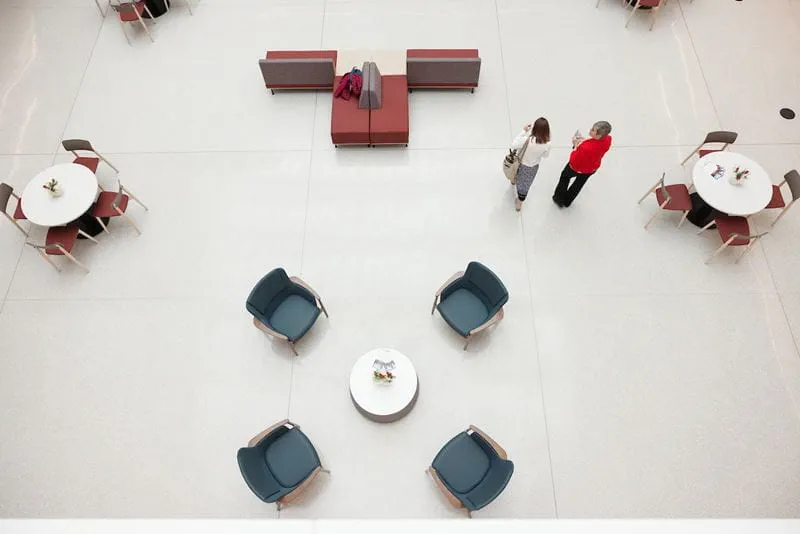 View of the Medical Education and Research Building atrium from above with two women walking by tables and chairs.