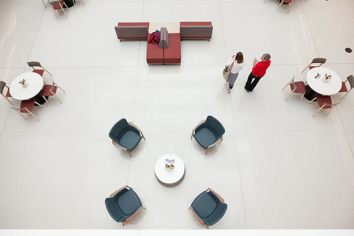 View of the Medical Education and Research Building atrium from above with two women walking by tables and chairs.