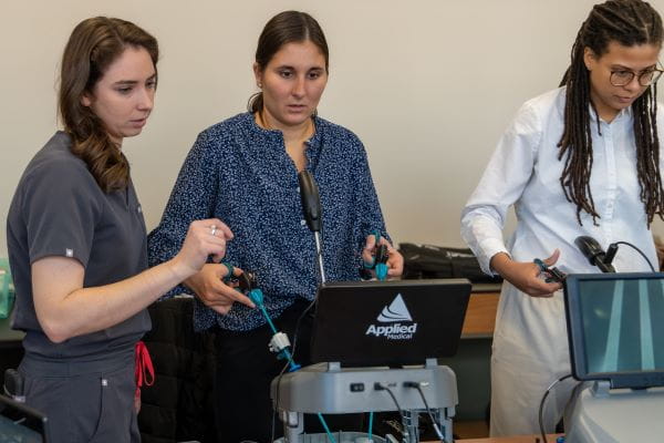 Miller helps medical students practice on a surgical simulation device.