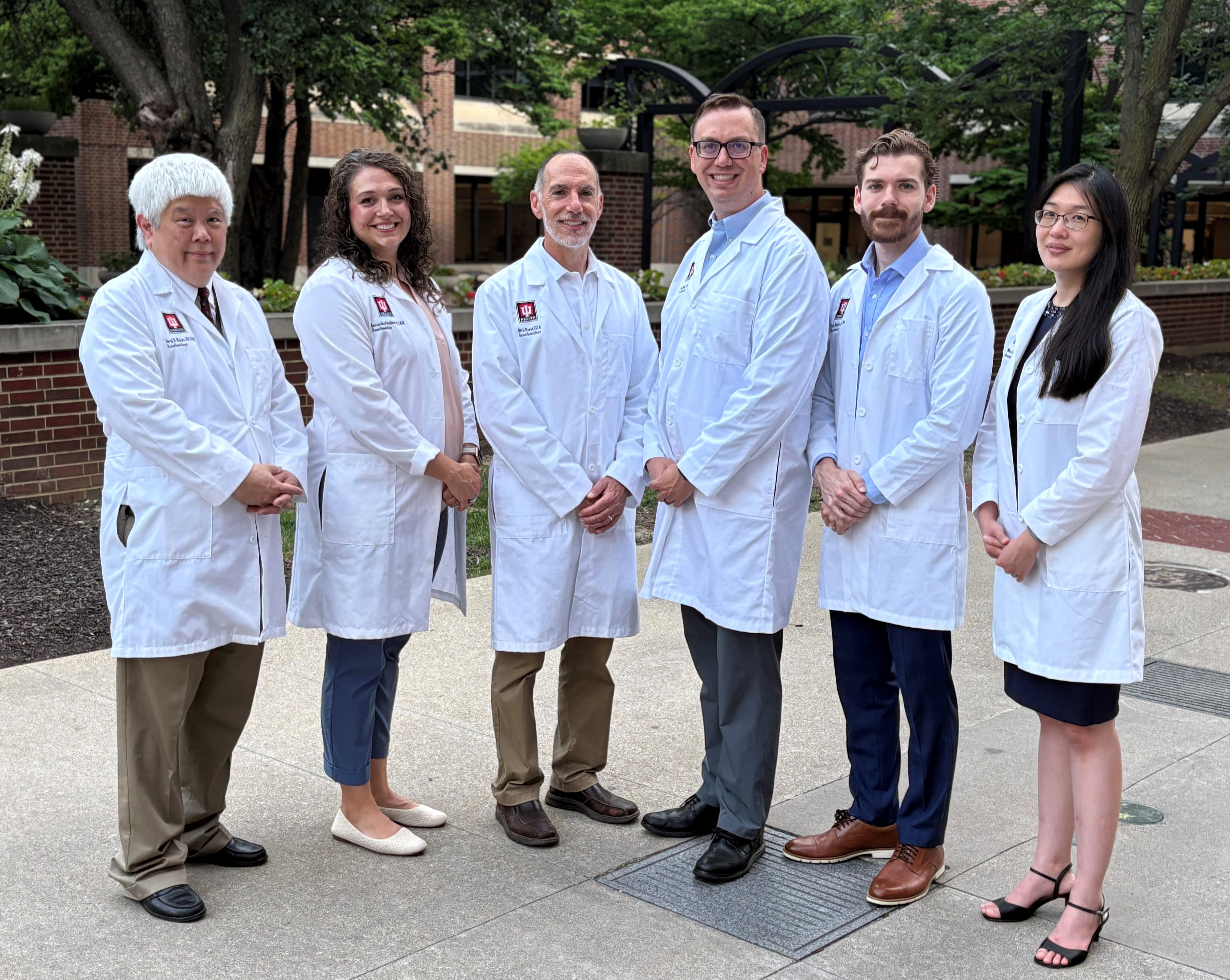 Six faculty in the Anesthesiologist Assistant Program pose in white coats for group photo