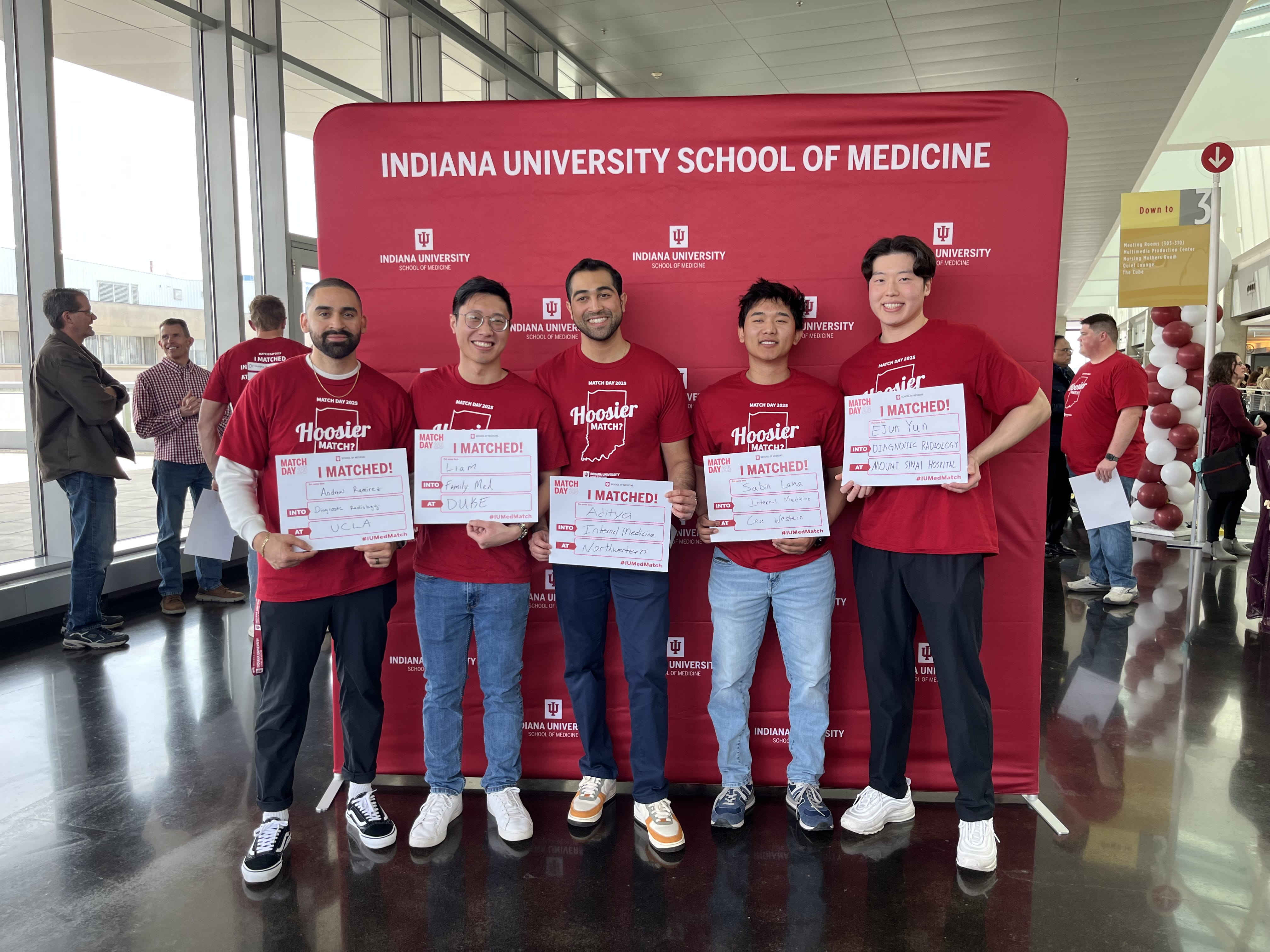 Aditya Belamkar (center) and other IU School of Medicine graduates show their matches during Match Day 2025 festivities on the campus if IU Indianapolis.