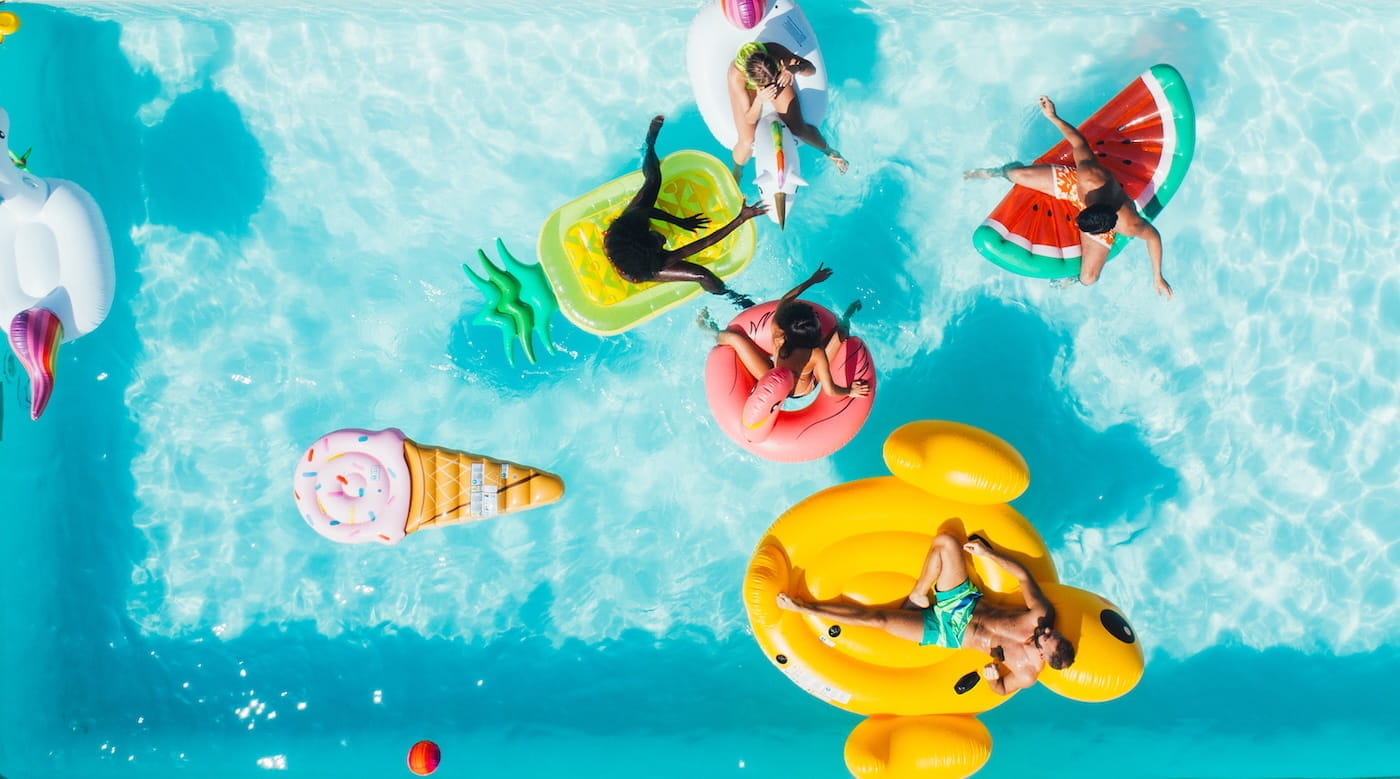 Birds-eye view of people in a swimming pool floating on fruit-shaped rafts
