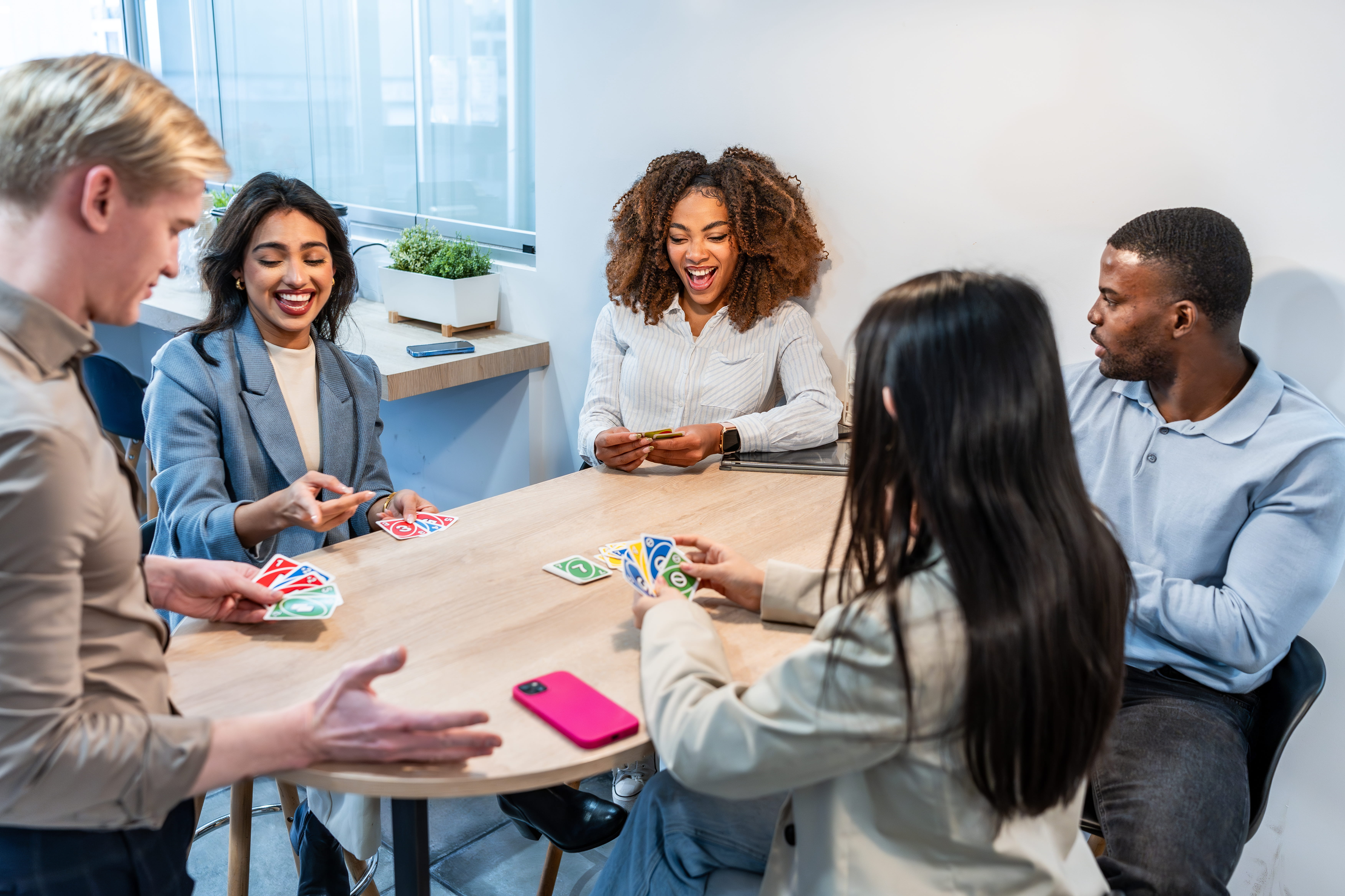 adults sitting at table playing UNO card game