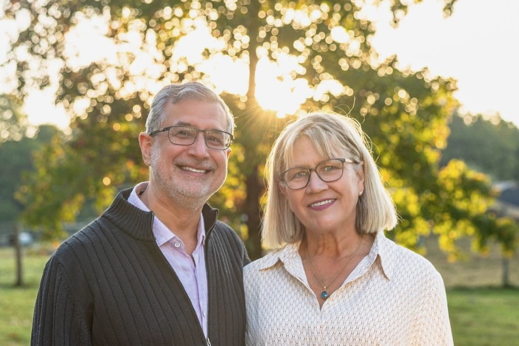 David and Janice Agarwal stand in front of a tree on their property on a sunny day