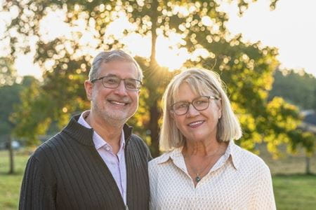 David and Janice Agarwal stand in front of a tree on their property on a sunny day