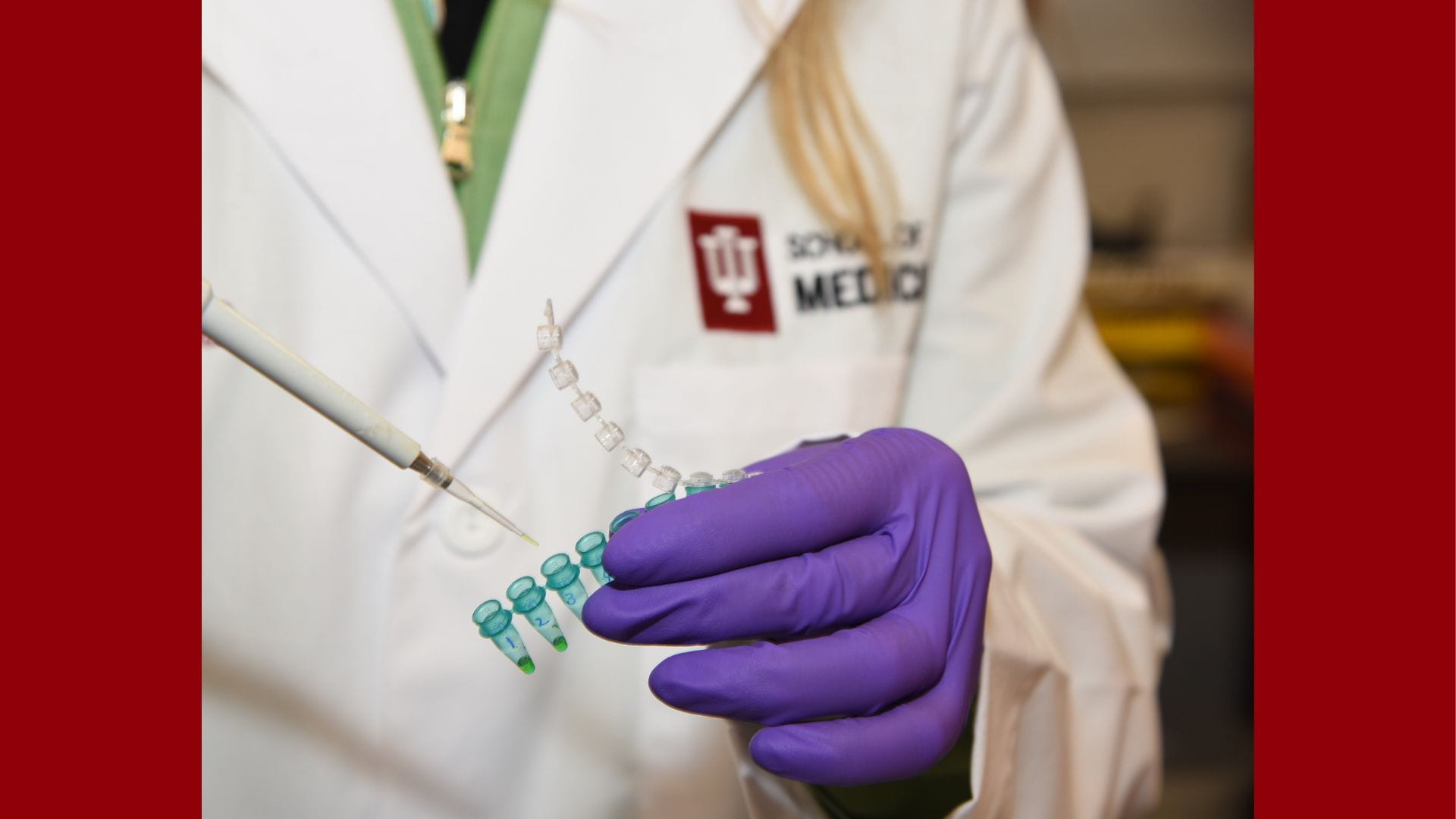Individual wearing an IU School of Medicine labcoat and working with equipment.
