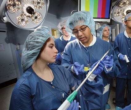 Brooke Stephanian and Sabin Karki in surgical scrubs in the OR, holding the Benegraft device