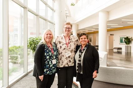 Donna Wilcock stands in between Elizabeth Head and Malu Tansey near a window during the 2025 symposium of the IU Center for Neurodegenerative Disorders.