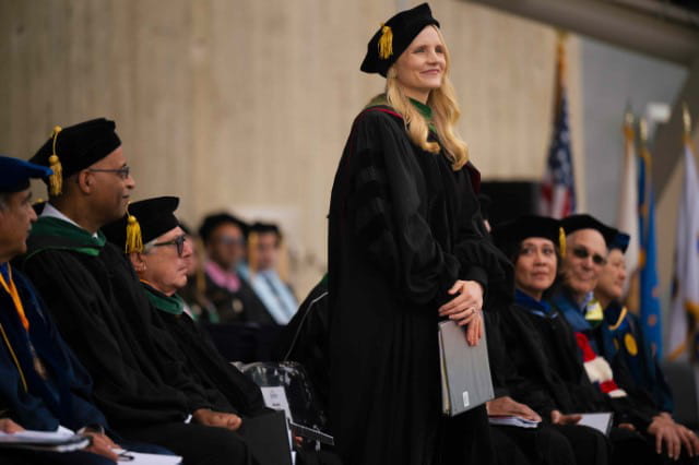 Laura Vater, in graduation regalia, speaks at the University of California San Diego Medical School commencement.