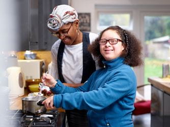 A woman and older child cook together in the kitchen