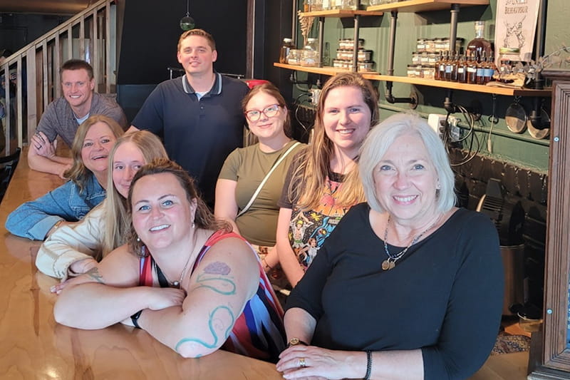 Barbara Frain seated at a distillery with a group of cytotechnology students