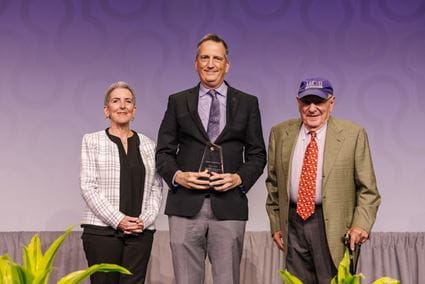 Cynthia Lemere and Zaven Khachaturian stand with Bruce Lamb, in the middle holding his award, during the 2025 Alzheimer's Association International Conference.