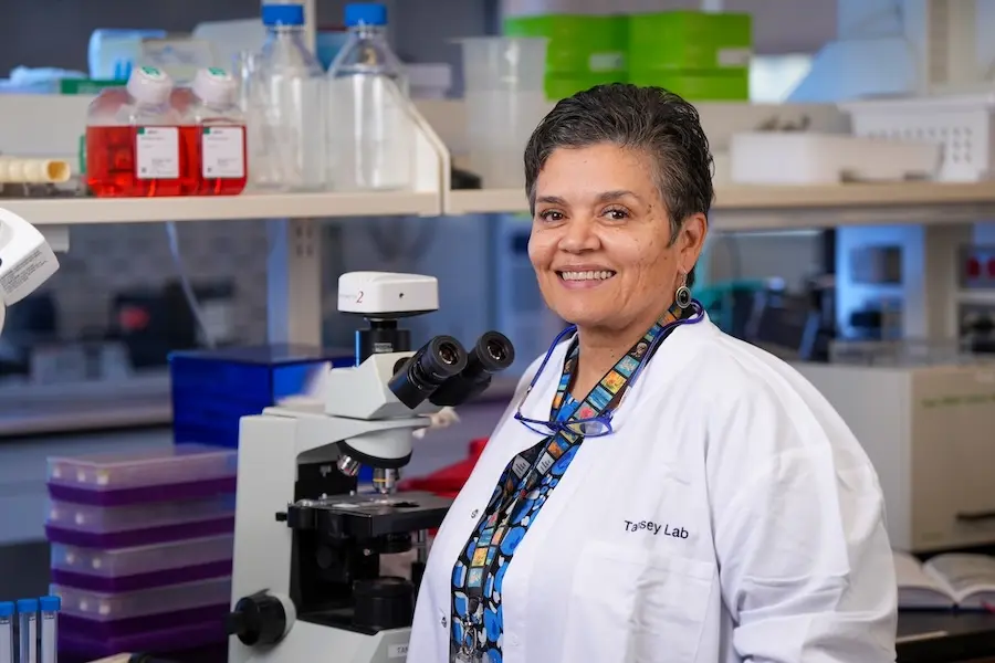 Malu Tansey, in white coat, poses in her research laboratory at IU School of Medicine.