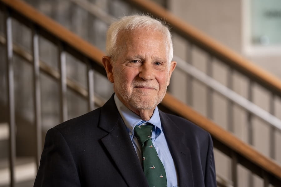 Portrait of Dr Patrick O'Neil wearing blue suit and green tie in front of a staircase at IU School of Medicine--West Lafayette