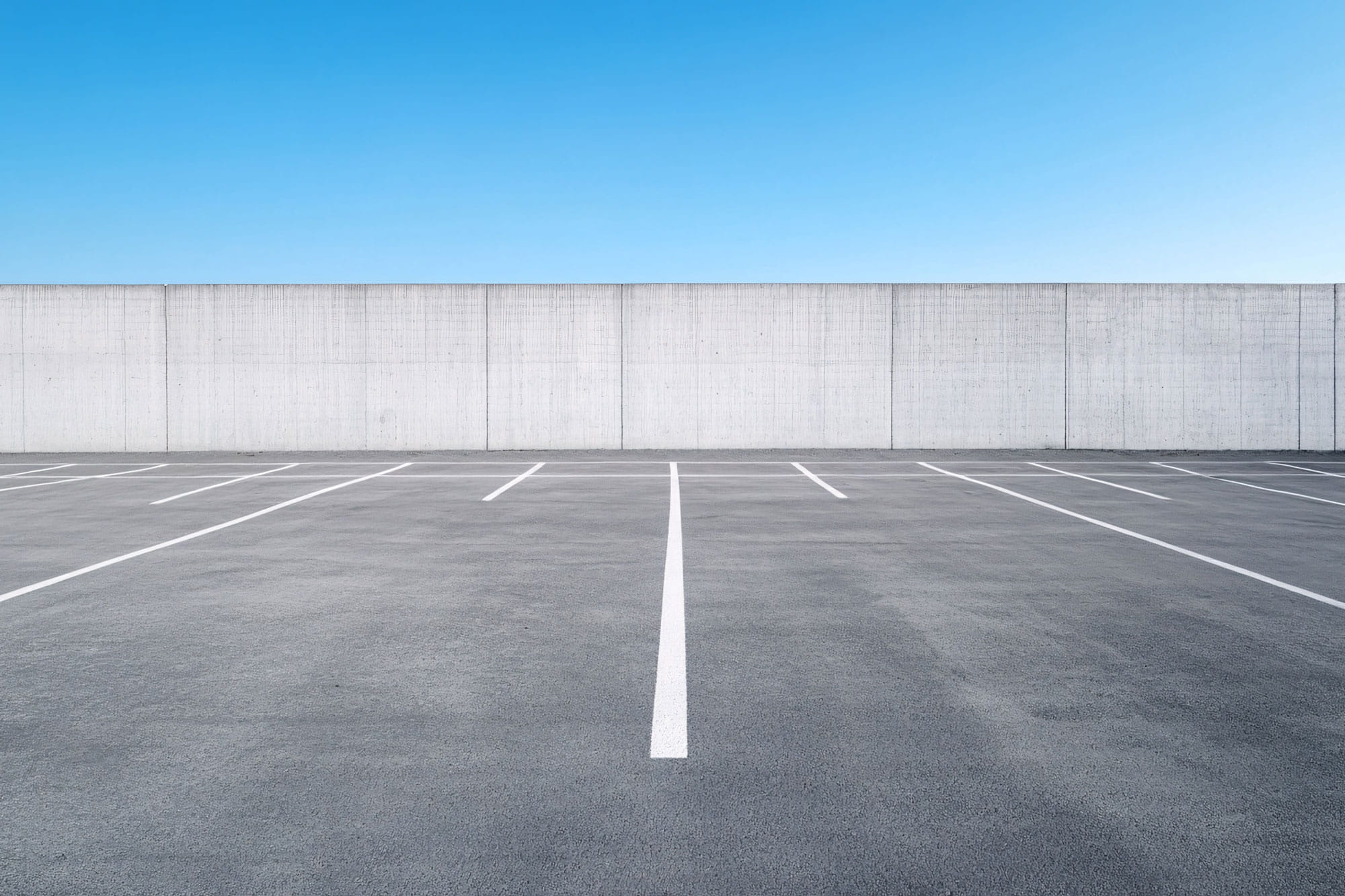 an empty paved parking lot with blue sky above