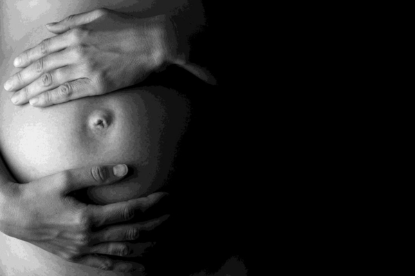 Expectant mother holding her belly, in low-key 
