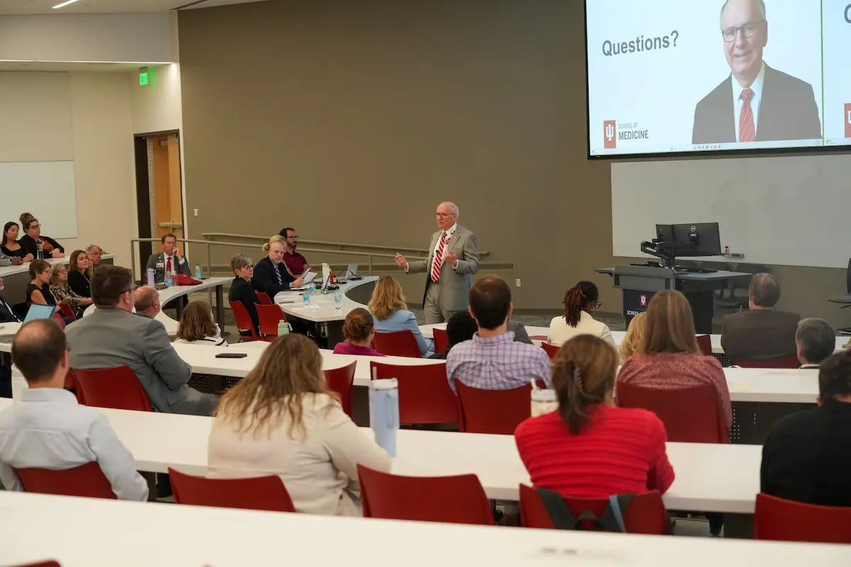 Dean Hess speaks at the podium to a full room of faculty and staff.