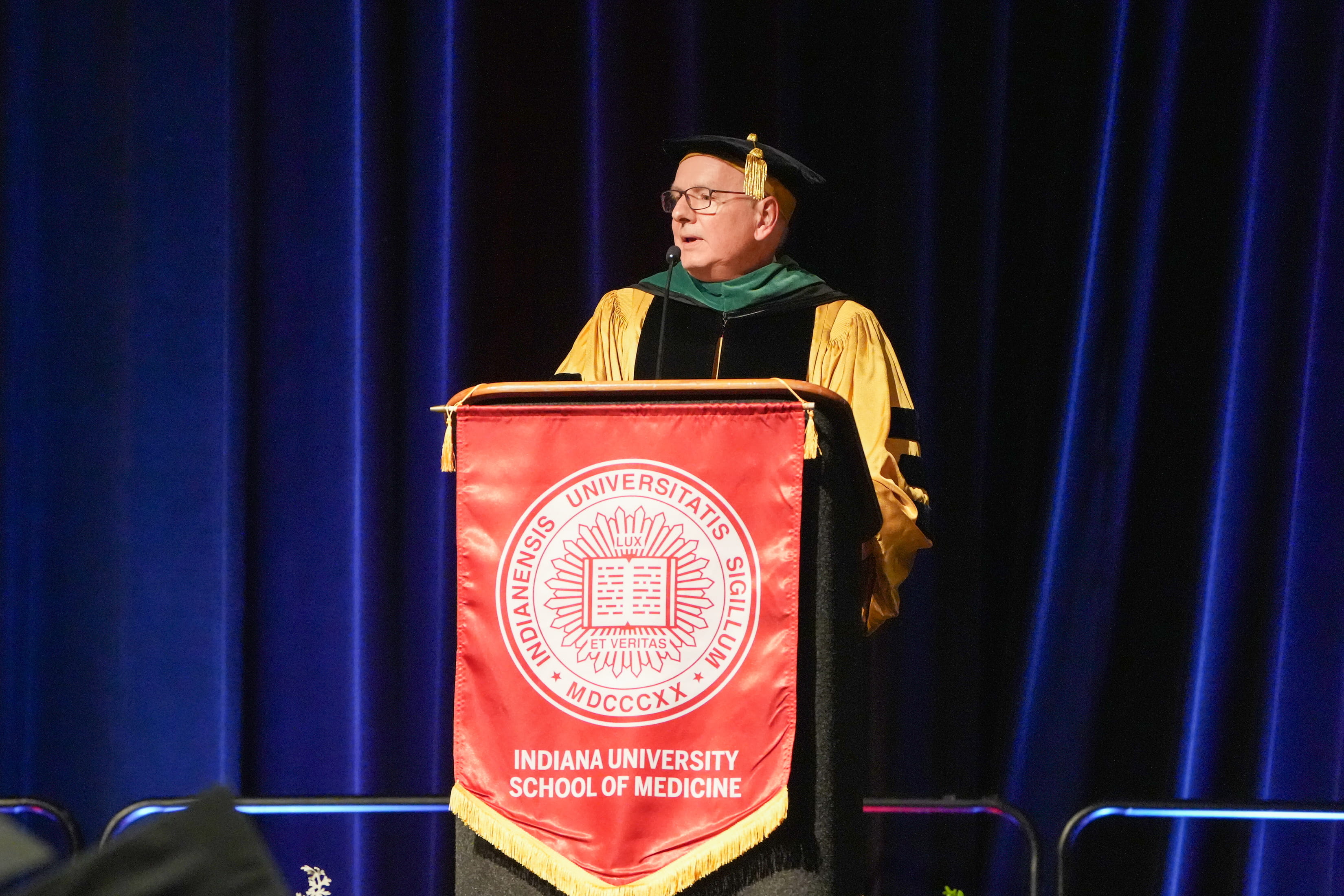 A speaker in robes stands behind a podium. 