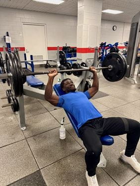 Mout-Maine Moustapha, in workout attire, at a bench press in the gym