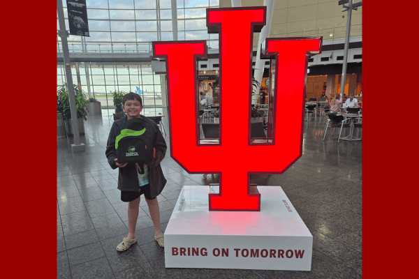 Heath Davis carrying his TADPOL backpack while standing next to a large model of the IU trident at the Indianapolis International Airport