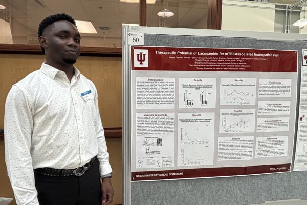 Mojeed Fagbemi, a medical student, stands in front of his poster.