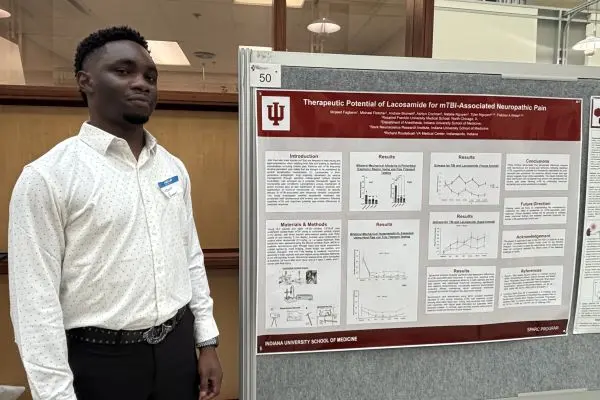 Mojeed Fagbemi, a medical student, stands in front of his poster.