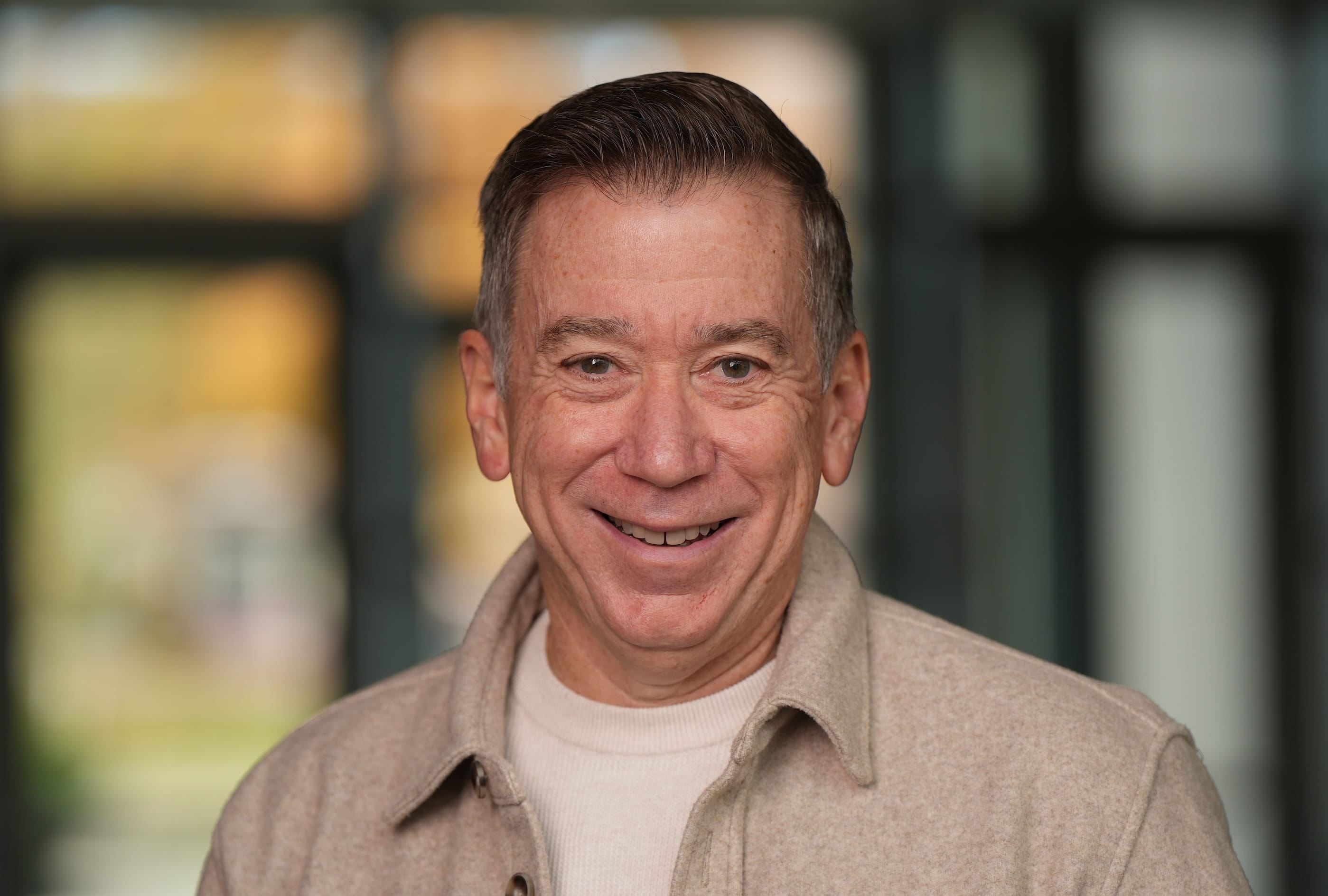 A headshot of a man in a tan shirt. 
