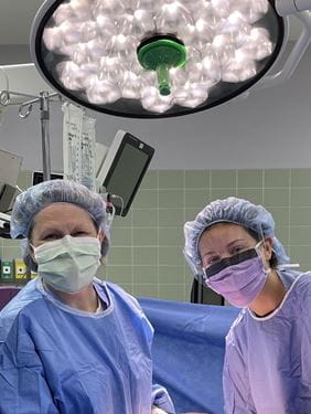 Lisa Landrum and Niki Minalt in surgical gear standing in the operating room