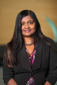 Head and shoulders shot of Meena Mahur wearing colorful blouse and black blazer