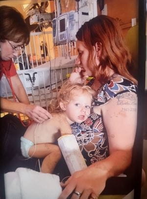 Madison as a baby on her mother's lap in the hospital with a doctor listening to her lungs with a stethoscope
