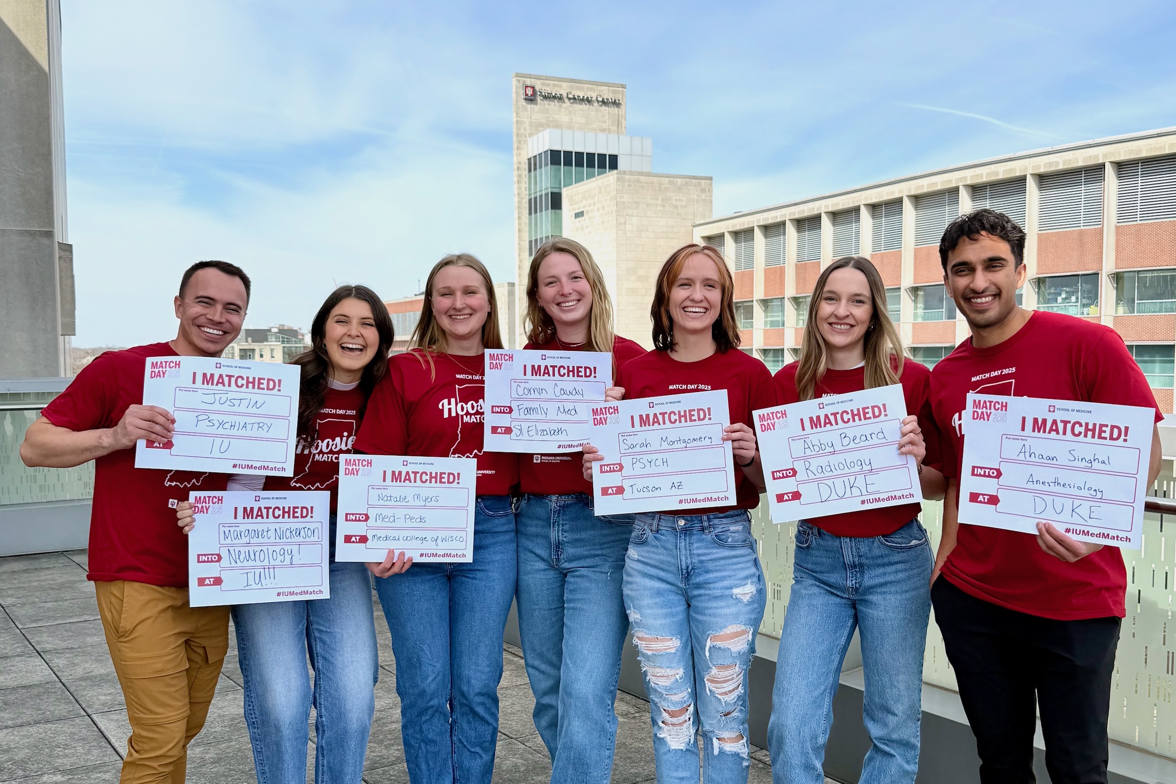 Seven IUSM 2025 graduates hold Match Day signs listing their residency matches.