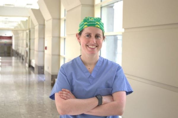 Orthopaedic Surgery Trauma fellow Michelle Lawson stands in a hallway in Methodist Hospital, with her arms folded and wearing a Seattle SuperSonics surgical cap.
