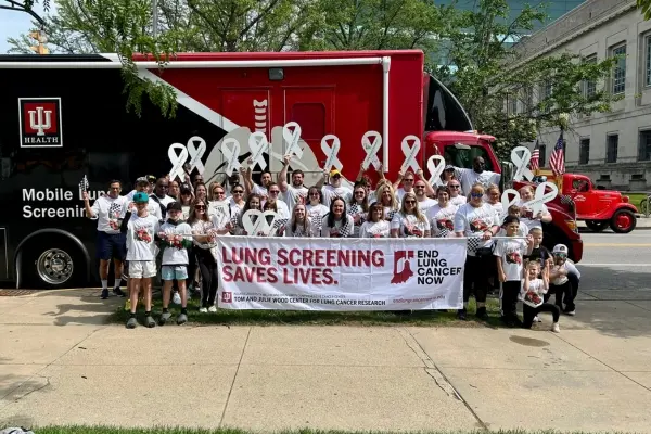 IU Health physicians, staff, and their family members smiling in front of the mobile cancer screening unit.