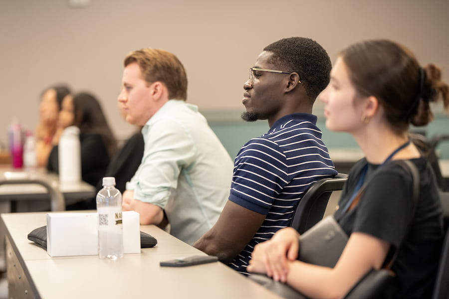 Mout-Maine Moustapha sits in a classroom at the IU School of Medicine next to two peers