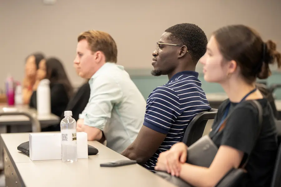 Mout-Maine Moustapha sits in a classroom at the IU School of Medicine next to two peers