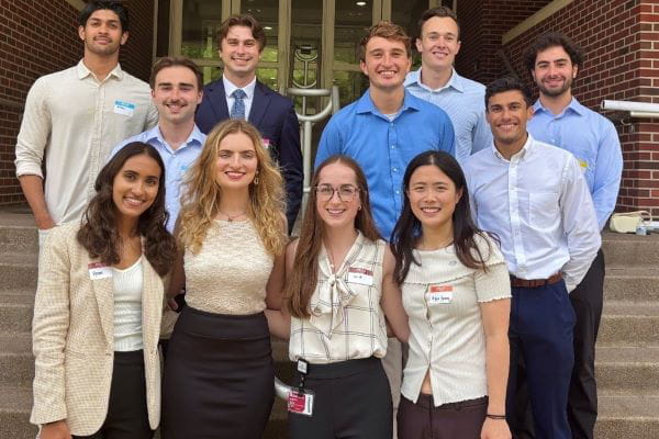 A group of people stand on the steps of a brick building. 