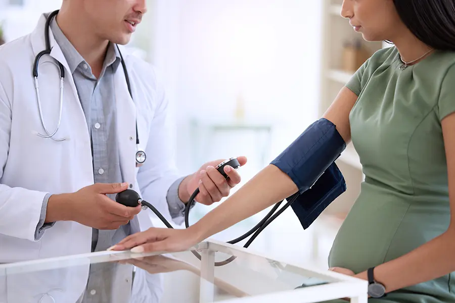 Pregnant person having blood pressure measured by doctor