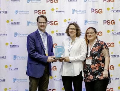Liz Zauber stands with two Parkinson's Foundation representatives as she receives an award for IU School of Medicine at a conference.
