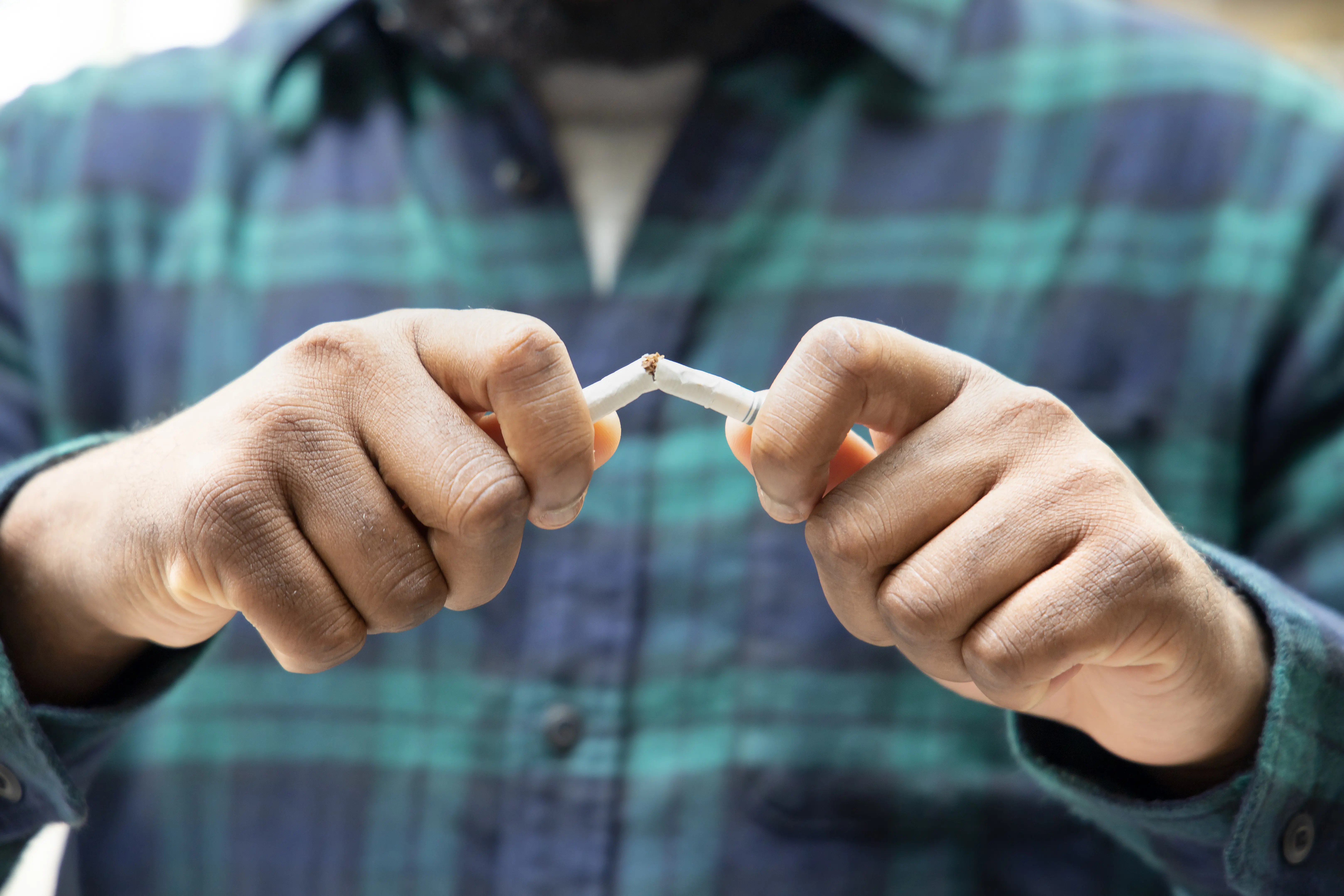 Two hands breaking a cigarette in half
