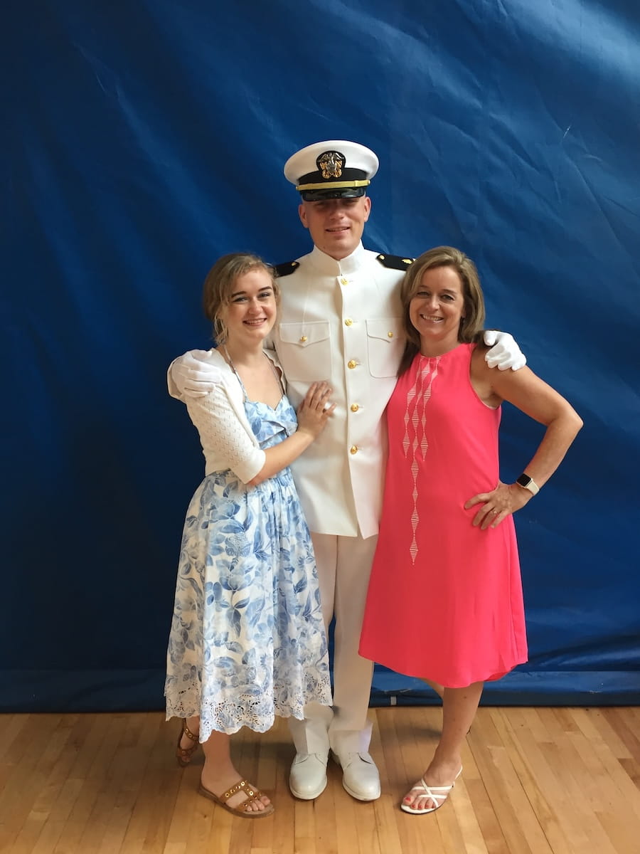 2025 graduate Meghan Russell with her brother Lt. Patrick Russell, in Navy whites, and their mother Paula Toth-Russell.