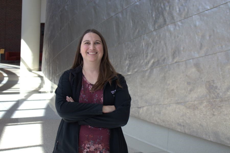 Sara Quinney smiles and stands with arms folded.